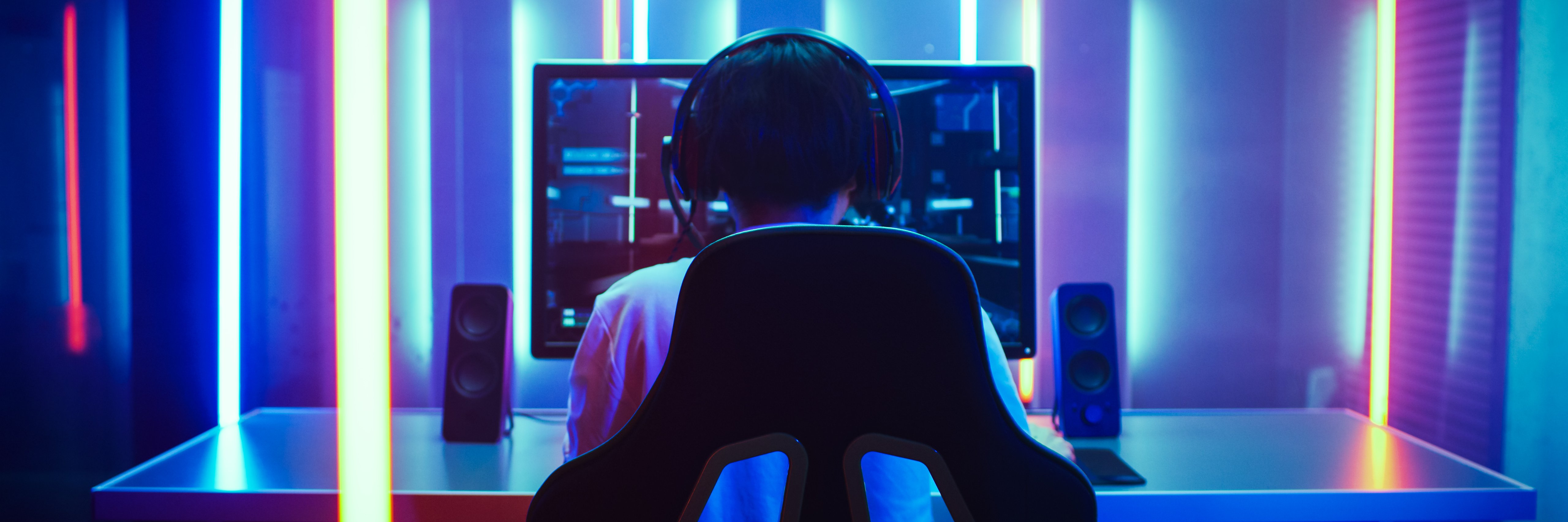 Gamer am PC vor Neon Hintergrund